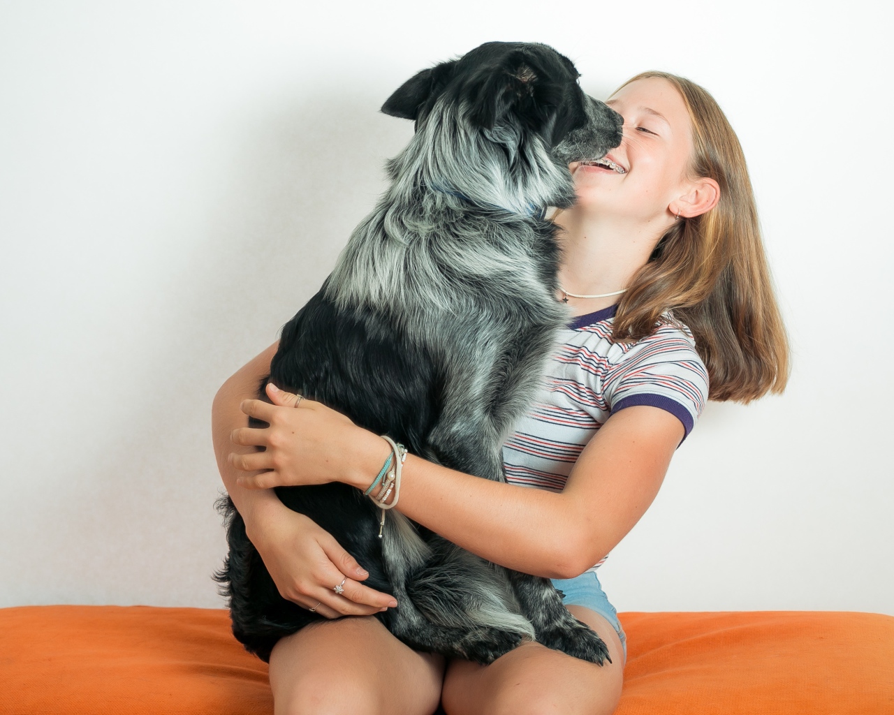 Веселая девочка с собакой в руках 