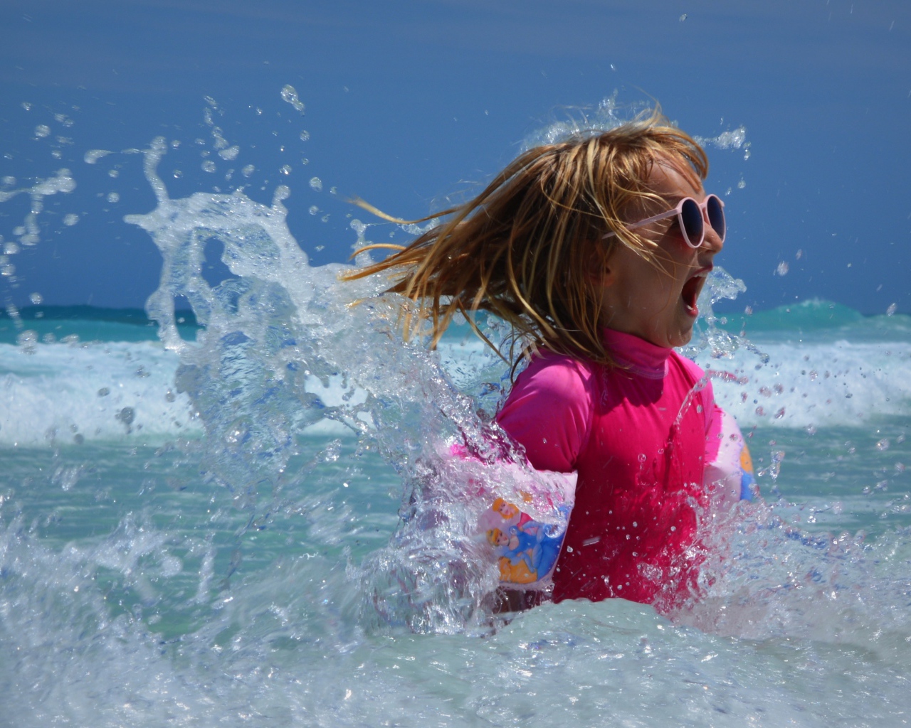 Веселая маленькая девочка купается в море летом