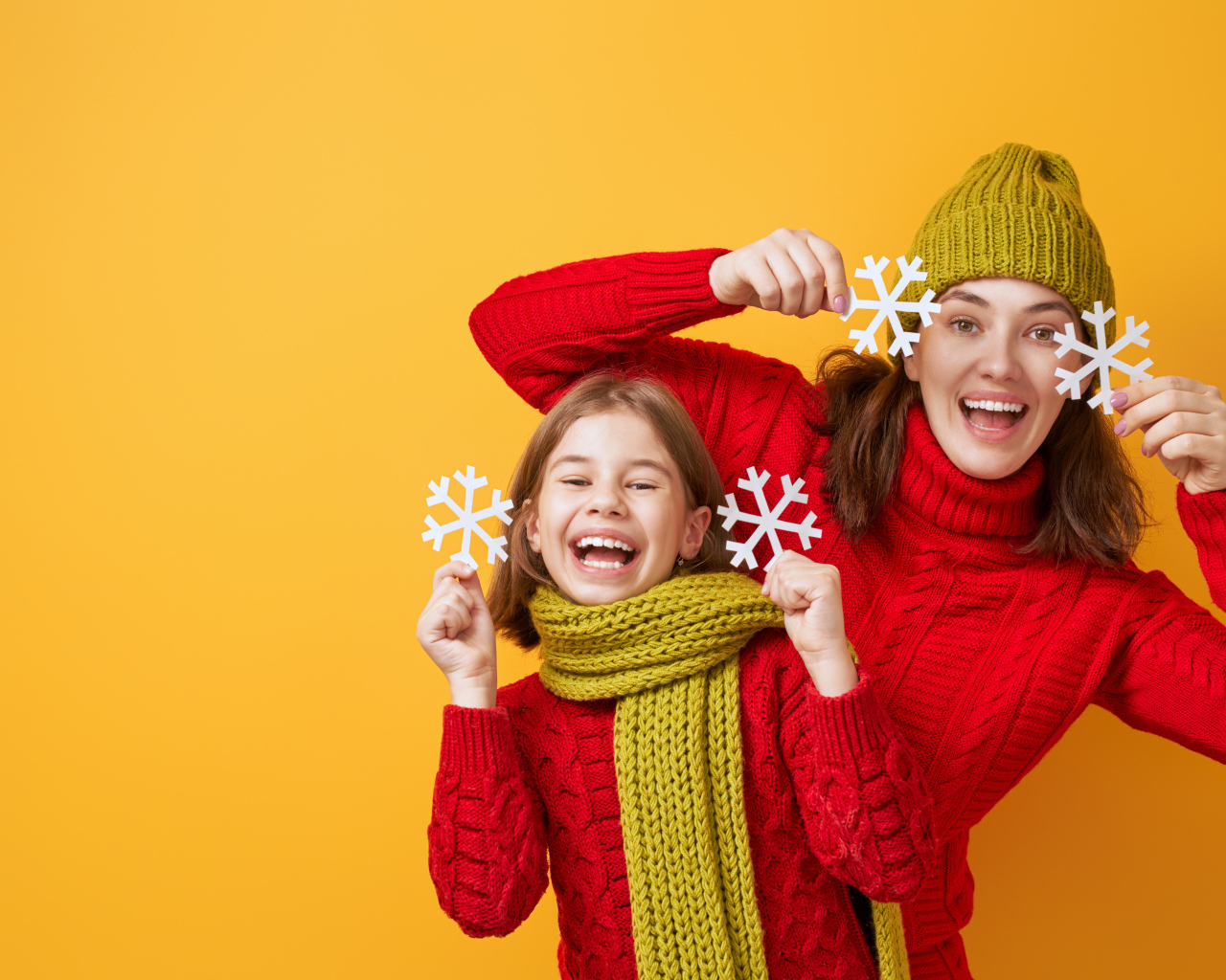 Веселые мама и дочка в красных свитерах на оранжевом фоне