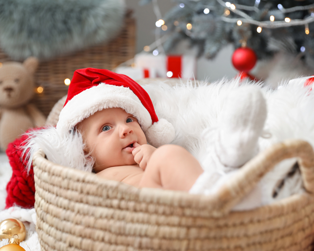 Милый малыш в шапке Санта Клауса лежит в корзине