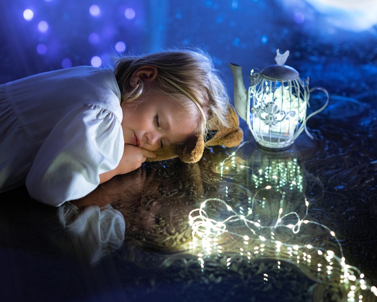 Милая маленькая девочка в белом платье спит на столе