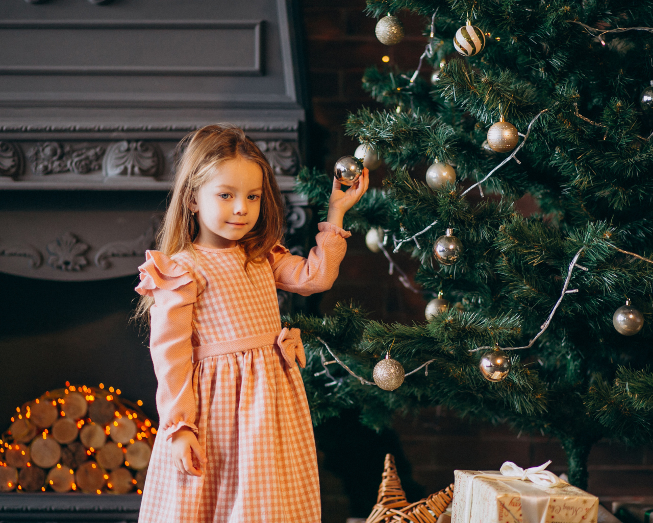 Милая маленькая девочка стоит у наряженной елки 