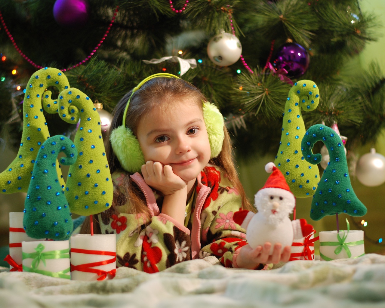 Милая маленькая девочка с игрушками под елкой 