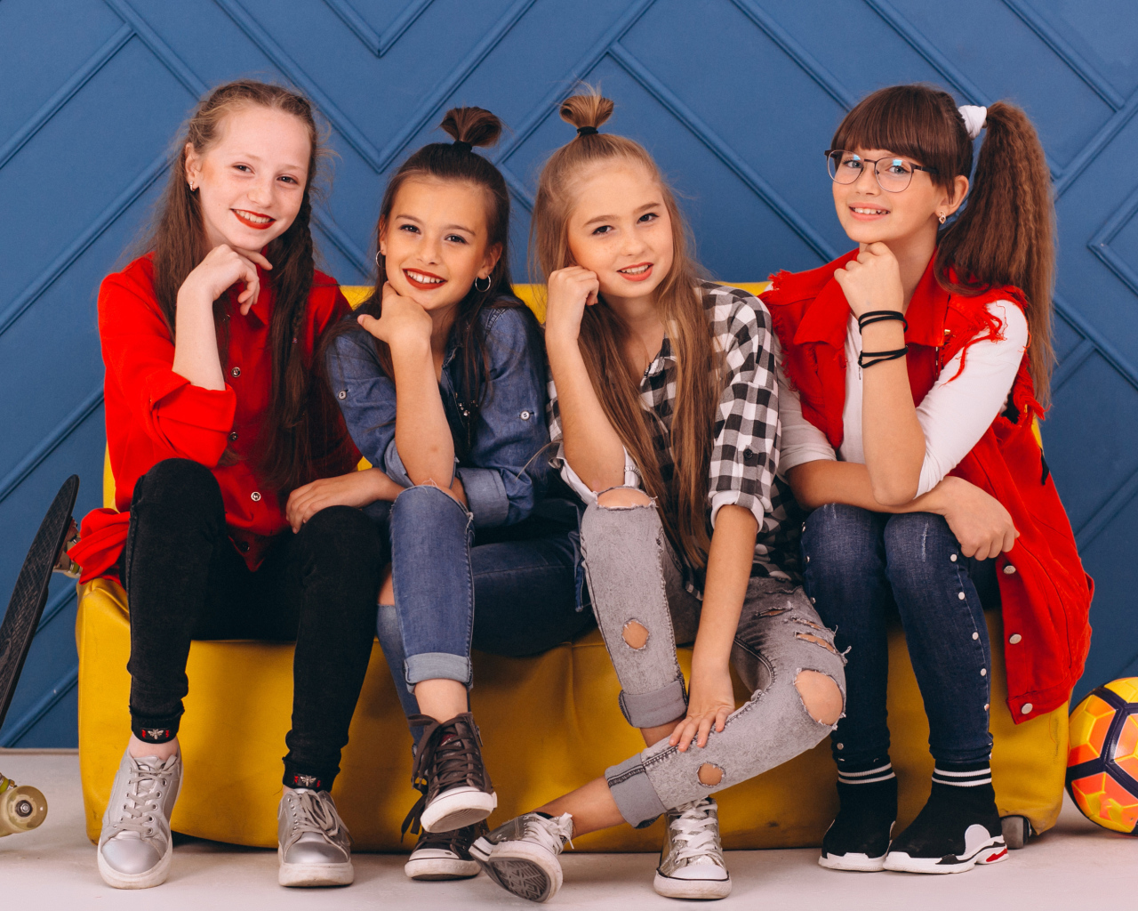 Четыре модных девочки сидят на диване 