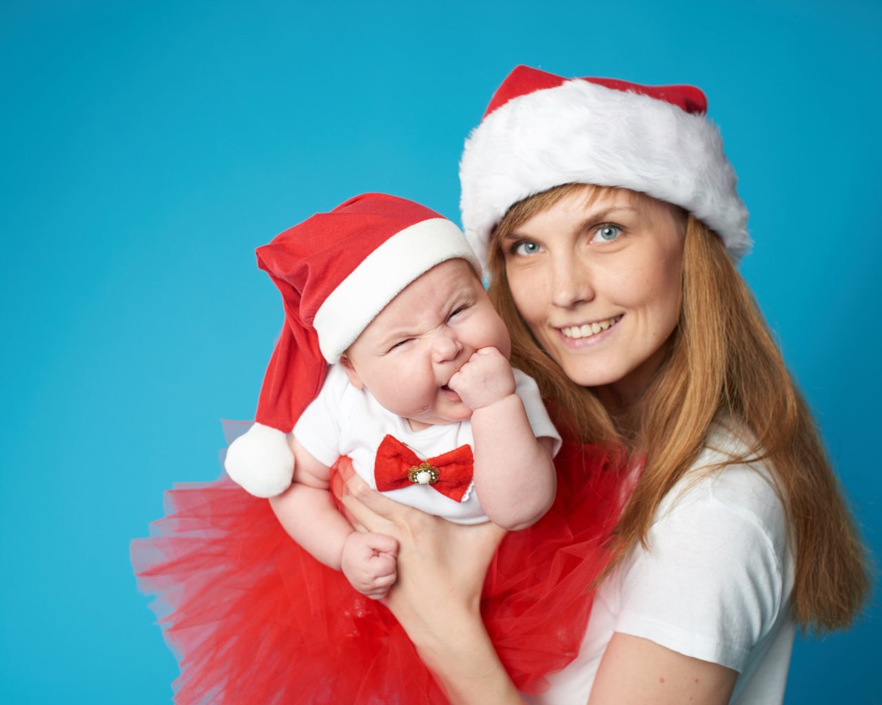 Смешной ребенок в новогоднем костюме на руках у мамы 