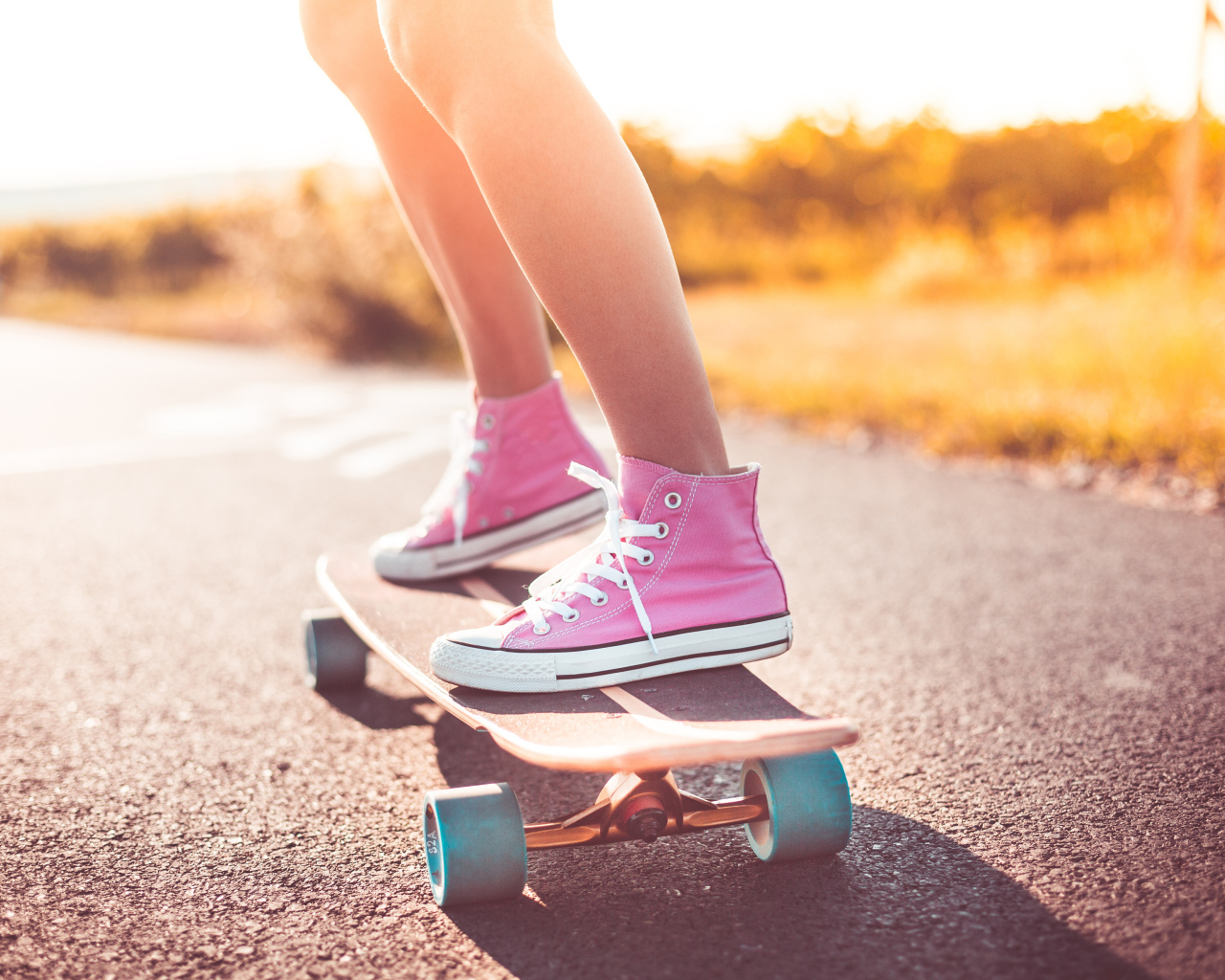 Девочка в розовых кедах едет на скейтборде
