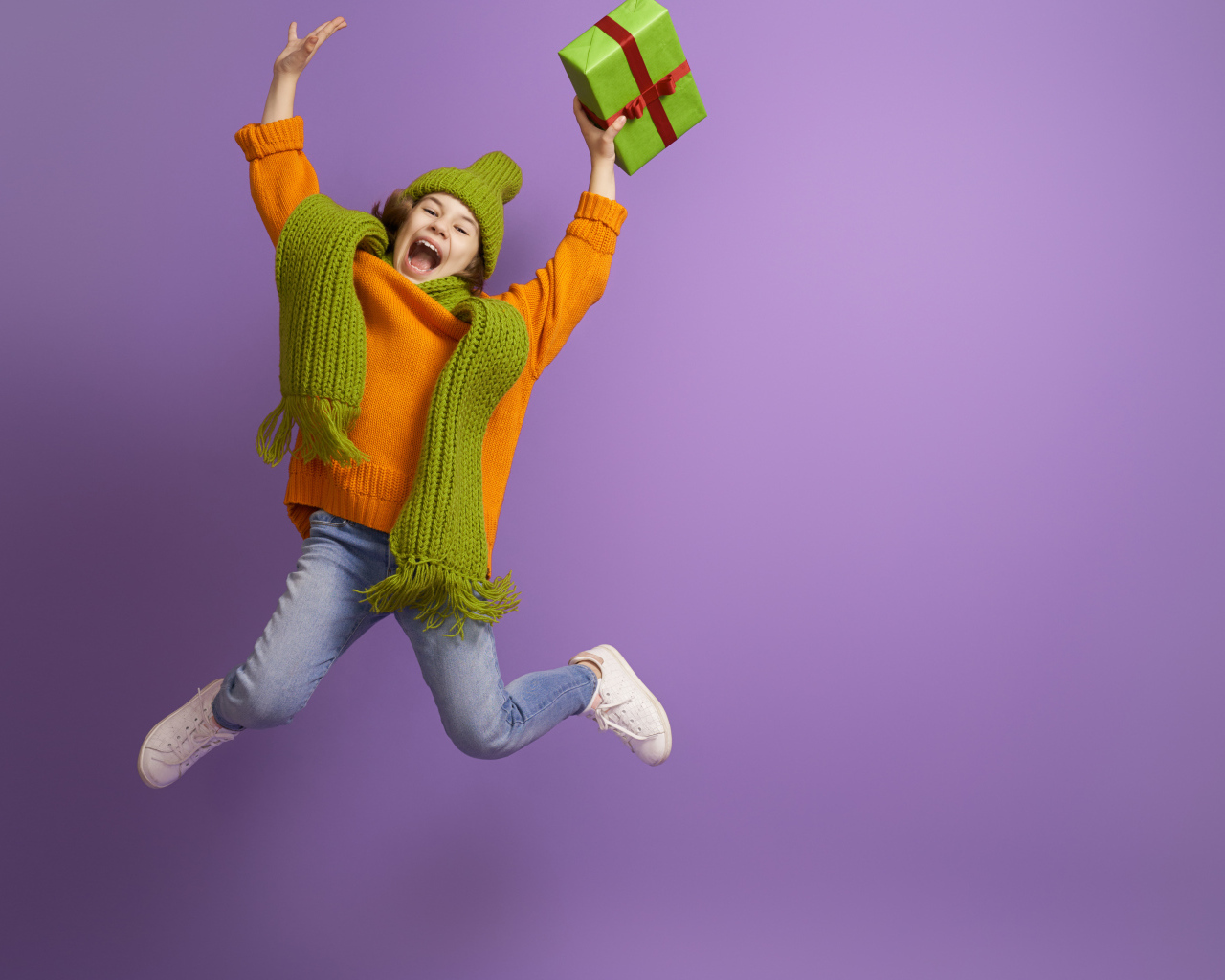 Счастливая девочка с подарком в руке на фиолетовом фоне