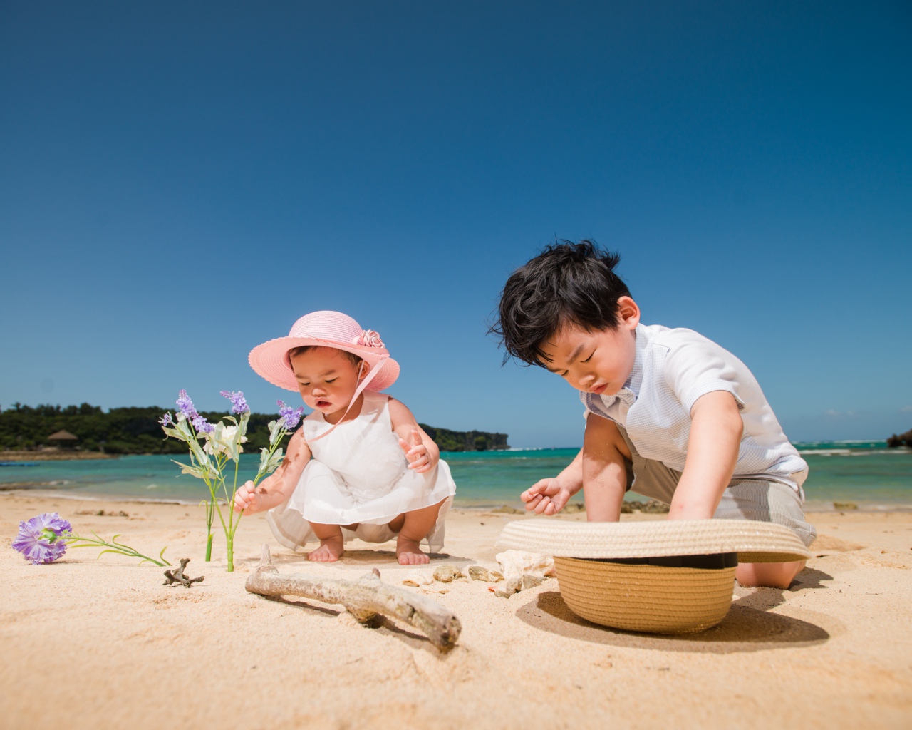 Маленькие дети азиаты играют на песке у моря 