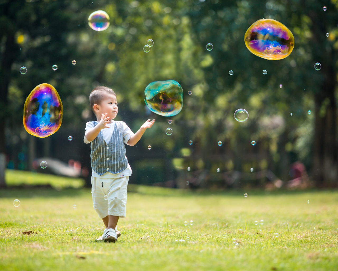 Маленький мальчик ловит мыльные пузыри