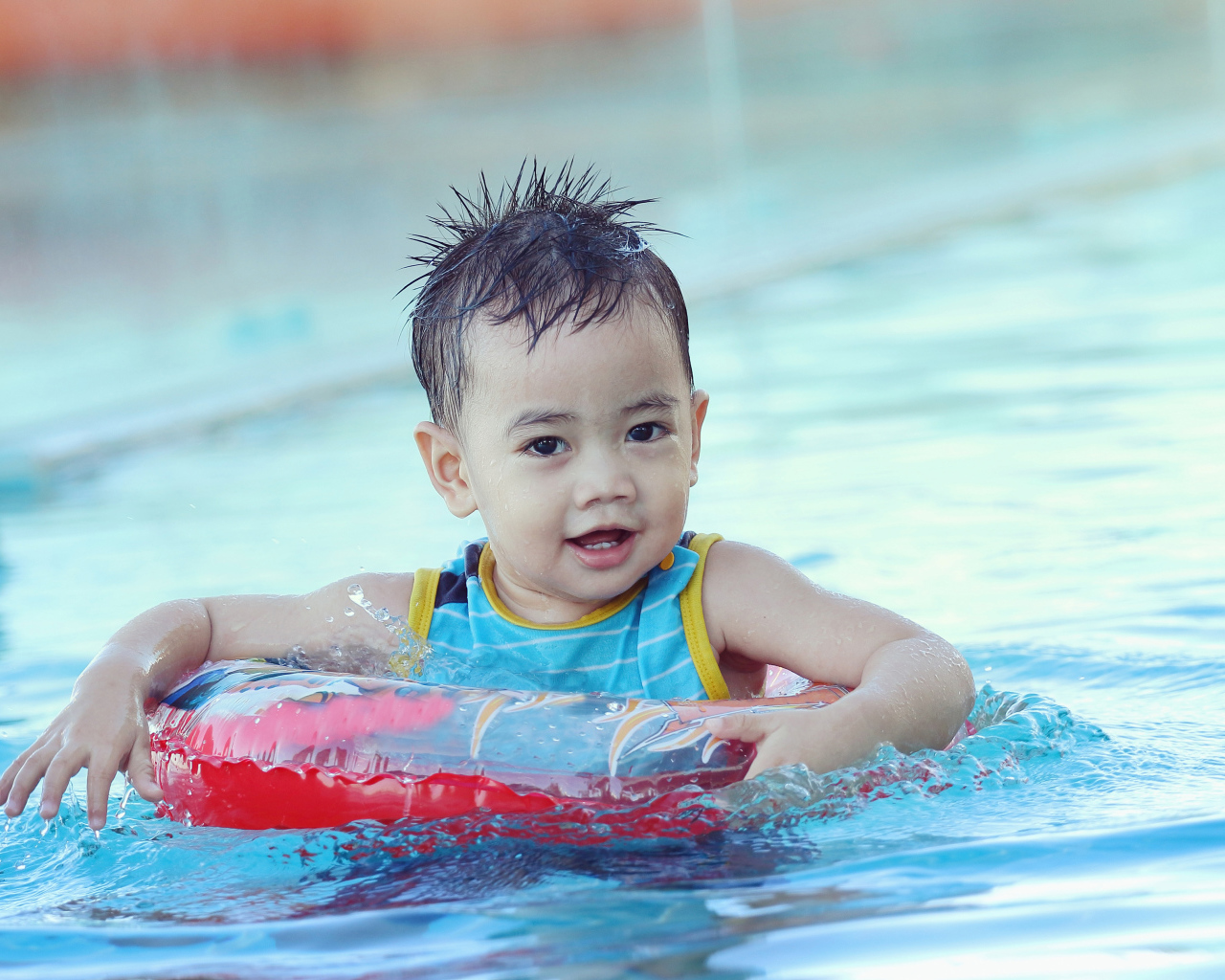 Маленький ребенок со спасательным кругом в бассейне 