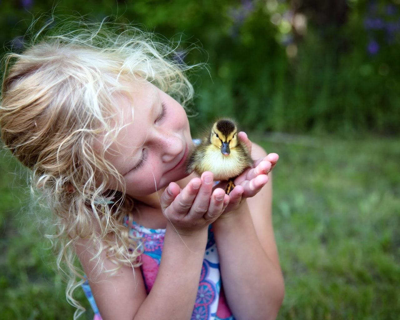 Маленькая милая девочка с утенком в руке