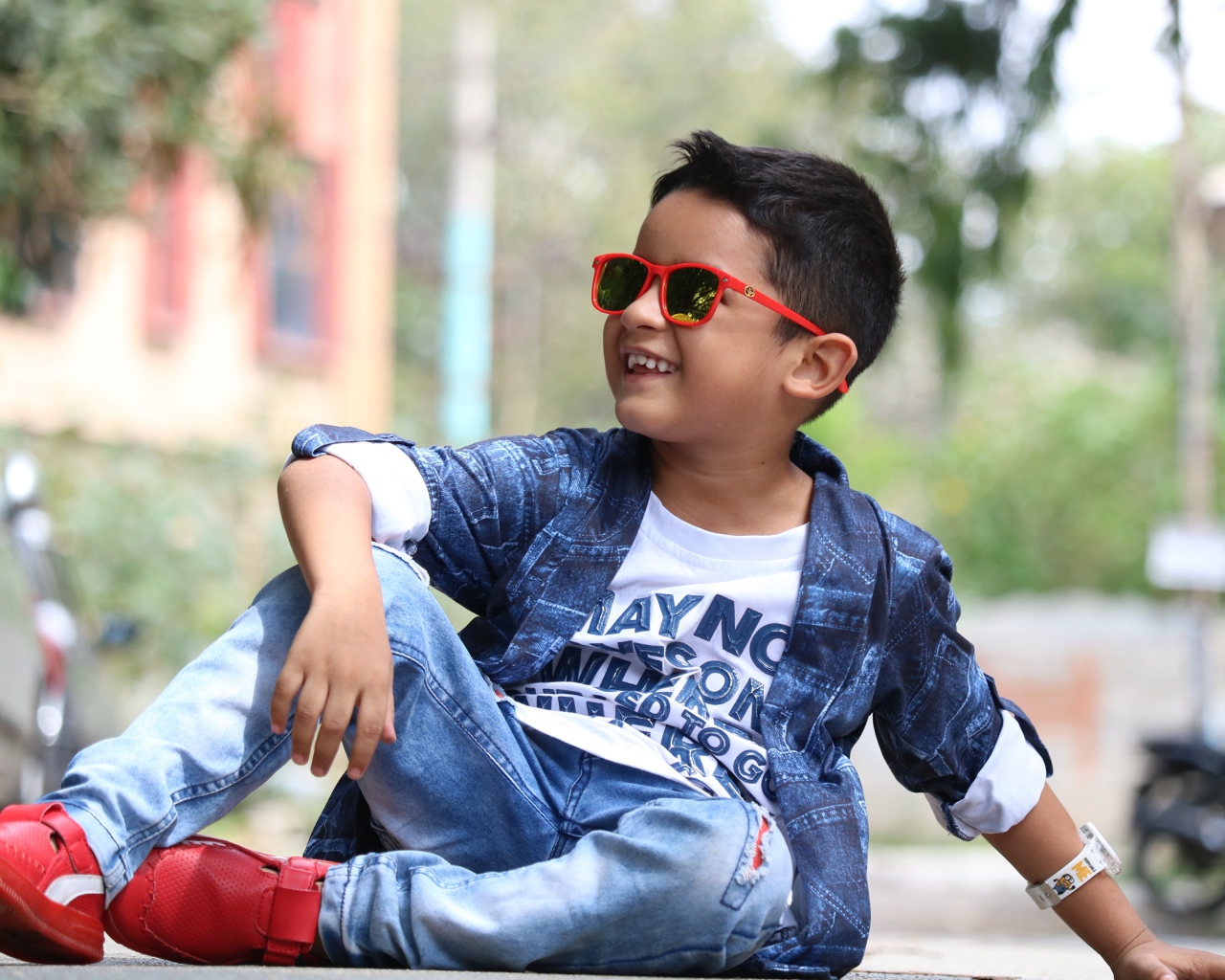 Маленький модный мальчик сидит на асфальте