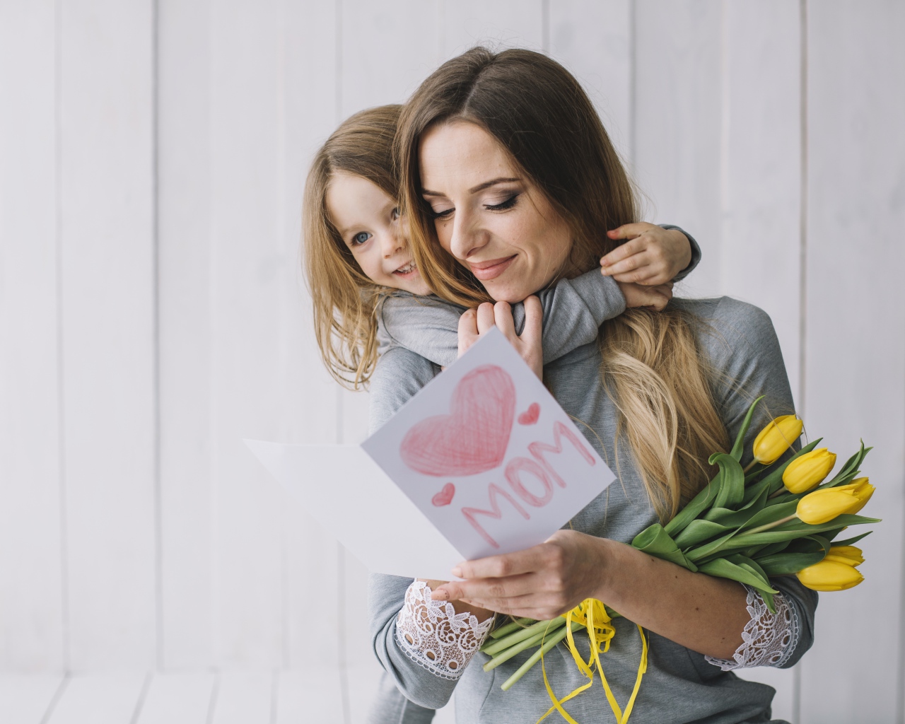 Маленькая девочка подарила маме открытку и букет тюльпанов