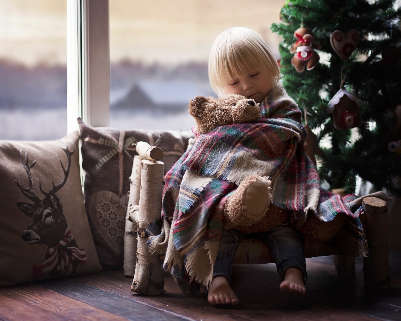 Маленькая девочка обнимает мишку у ели