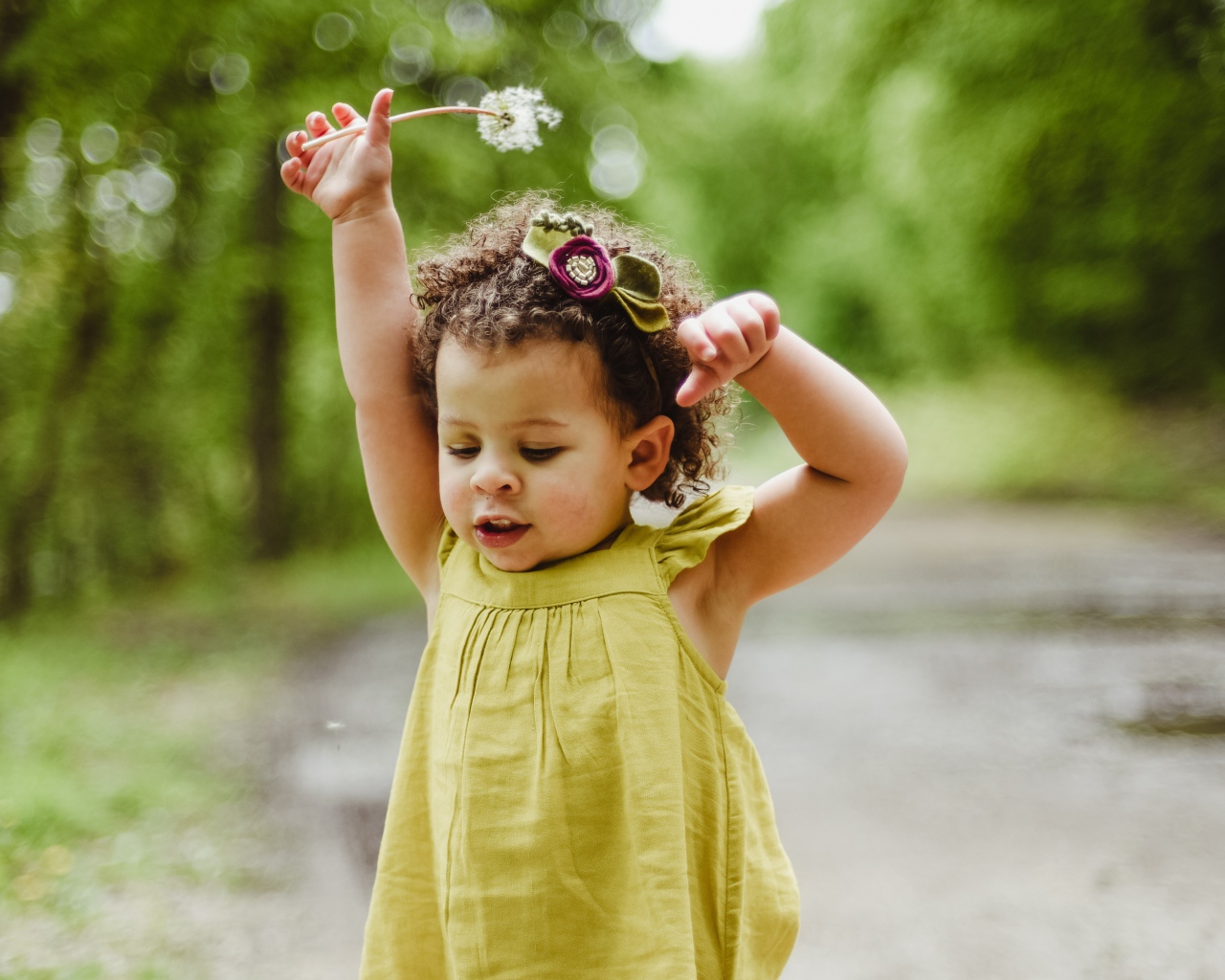 Маленькая девочка в платье с одуванчиком в руке