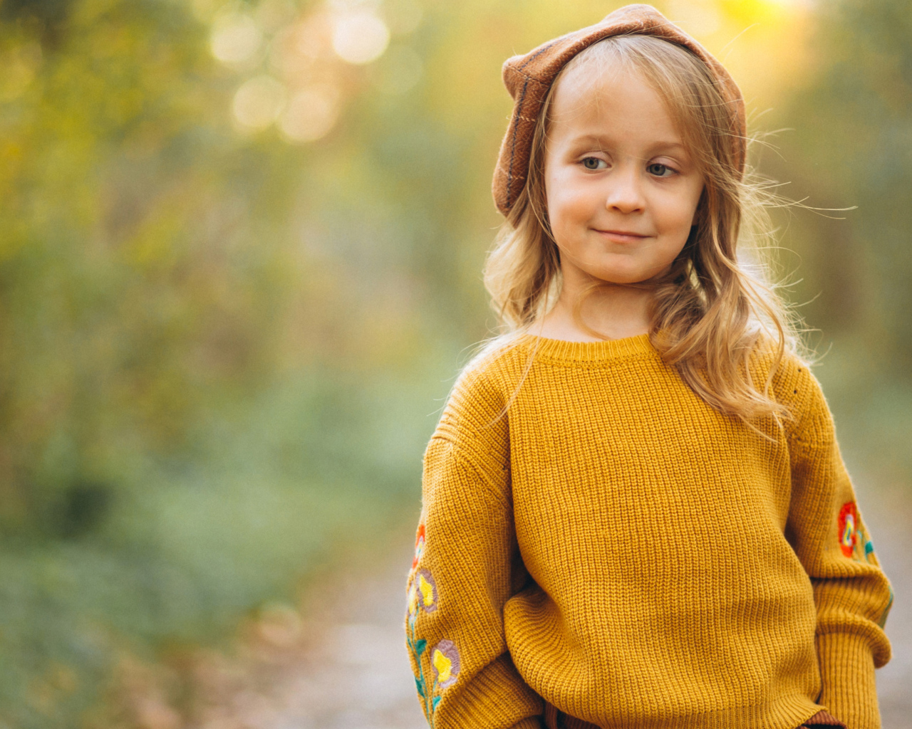 Маленькая девочка в свитере гуляет в лесу