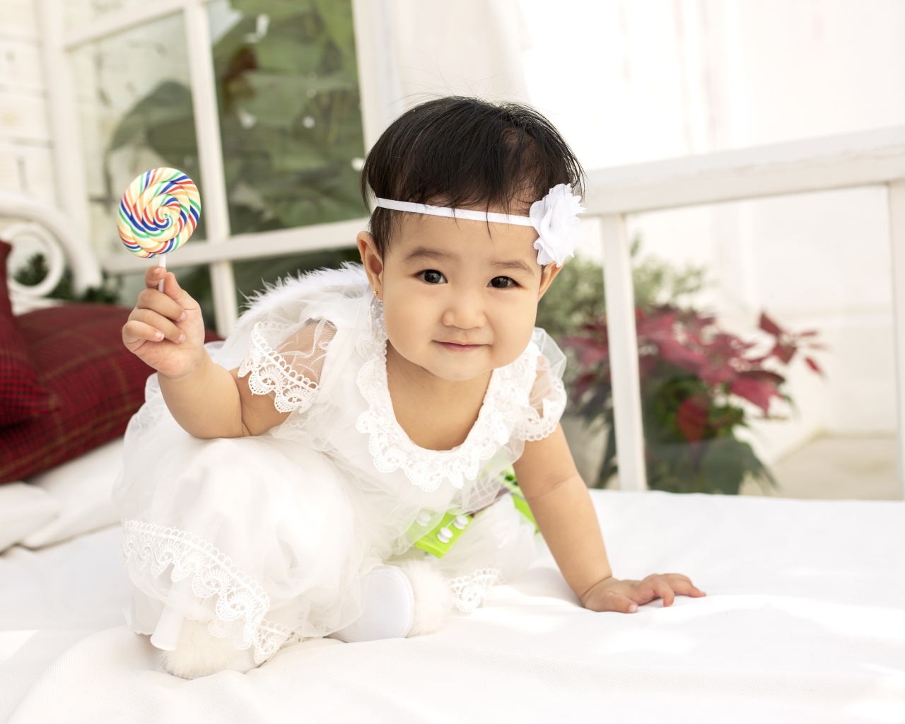 Маленькая девочка в белом платье с леденцом в руке