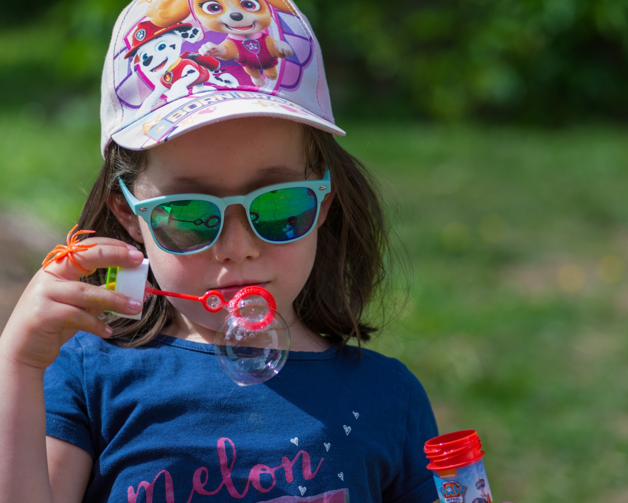 Маленькая девочка в очках с мыльными пузырями