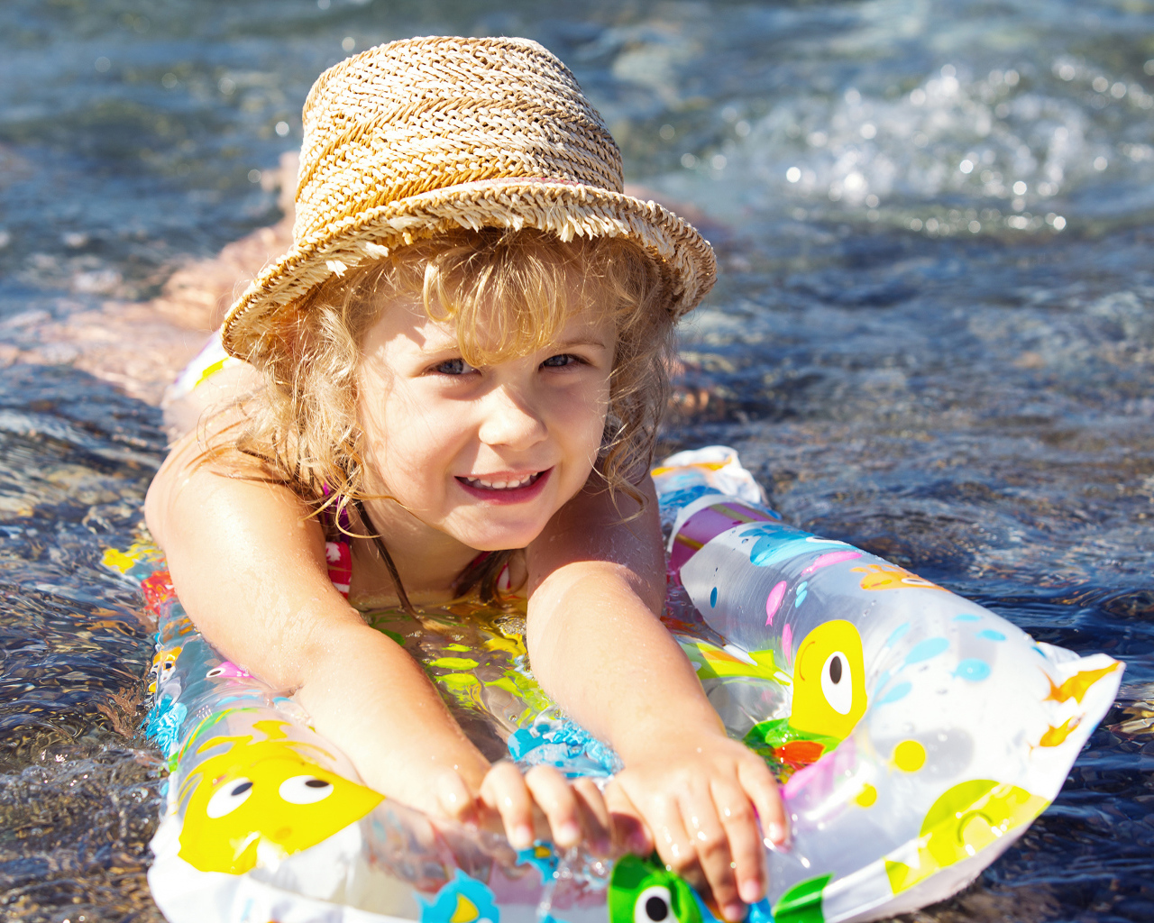 Маленькая девочка на надувном матрасе в воде