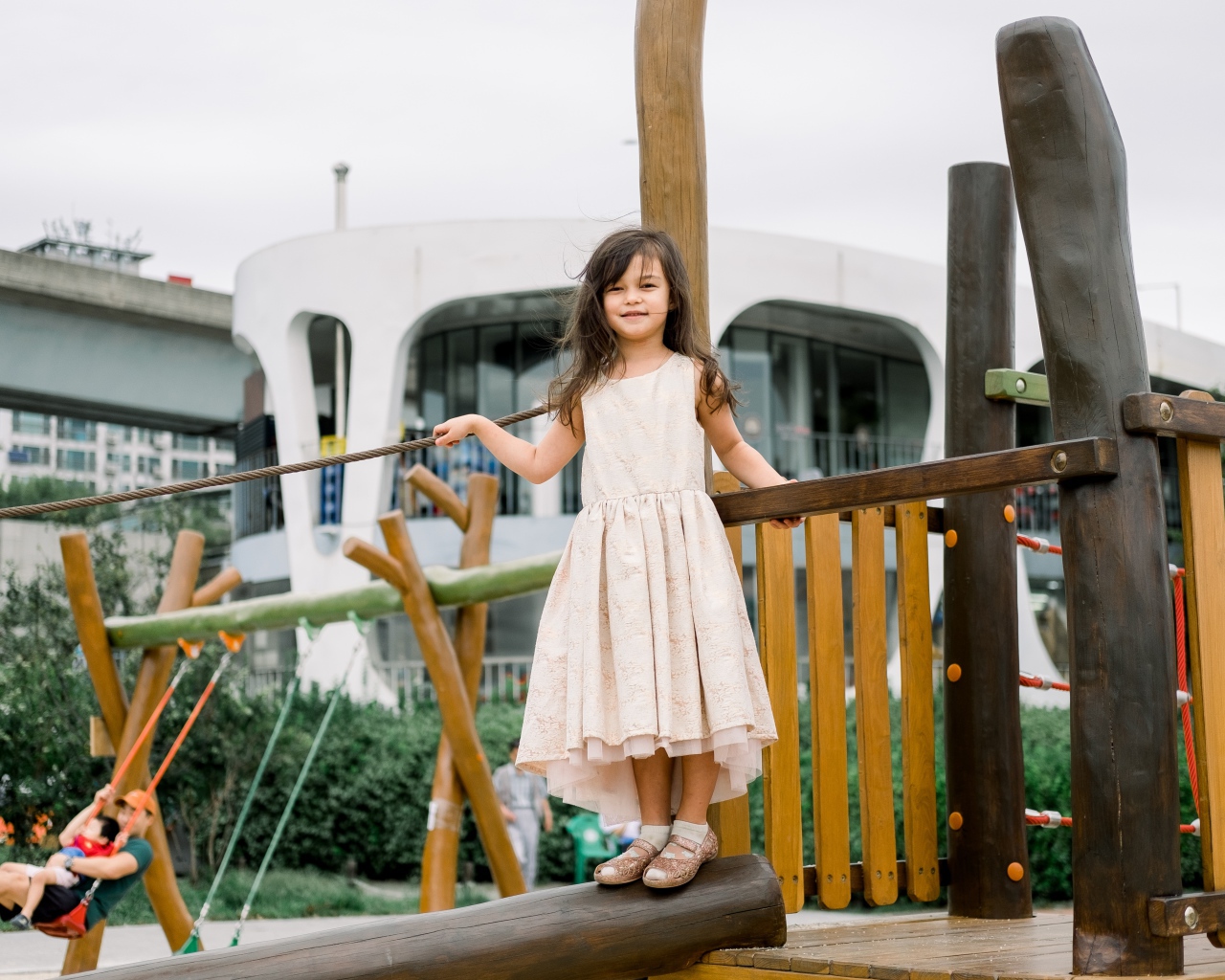 Маленькая девочка стоит на детской площадке 