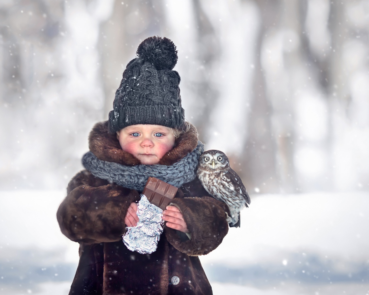 Маленькая девочка с шоколадкой в руках на улице зимой
