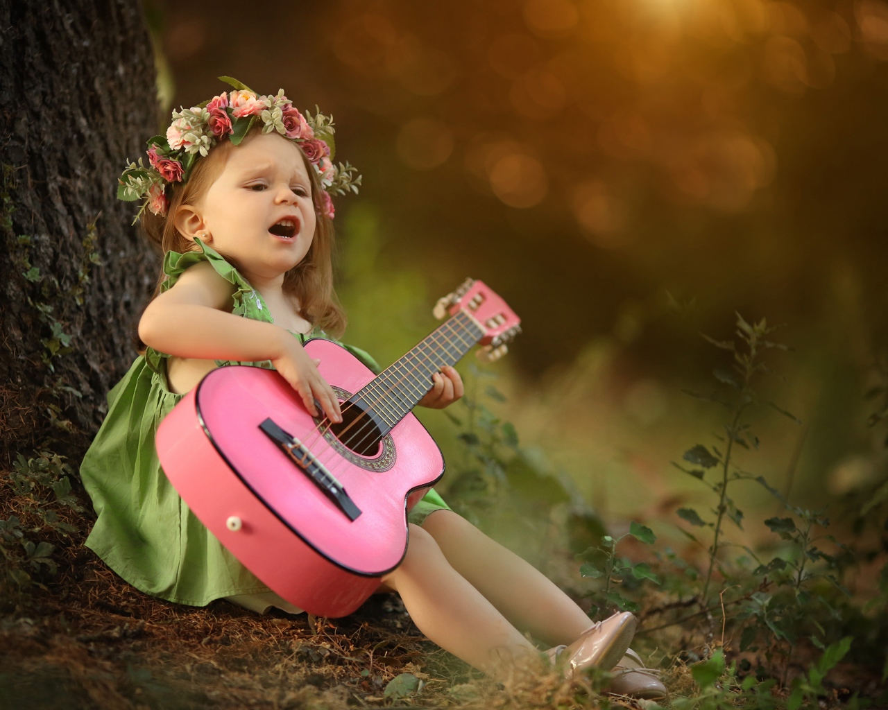 Маленькая девочка с гитарой под деревом 