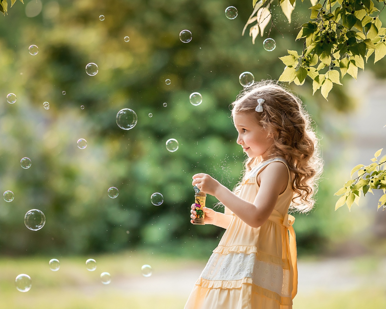 Маленькая девочка с мыльными пузырями в саду 