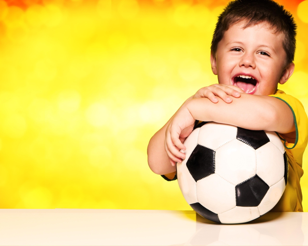 Маленький довольный мальчик с футбольным мячом