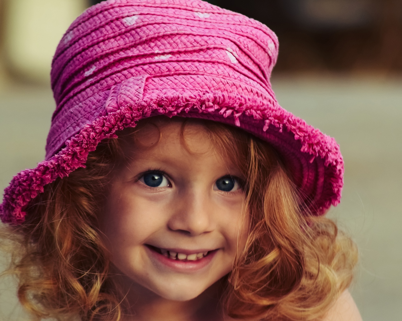 Маленькая улыбающаяся девочка в розовой шляпе