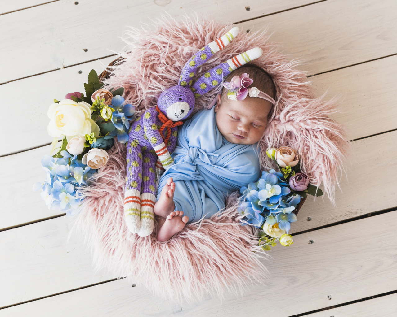 Спящий грудной ребенок с игрушкой в корзине 