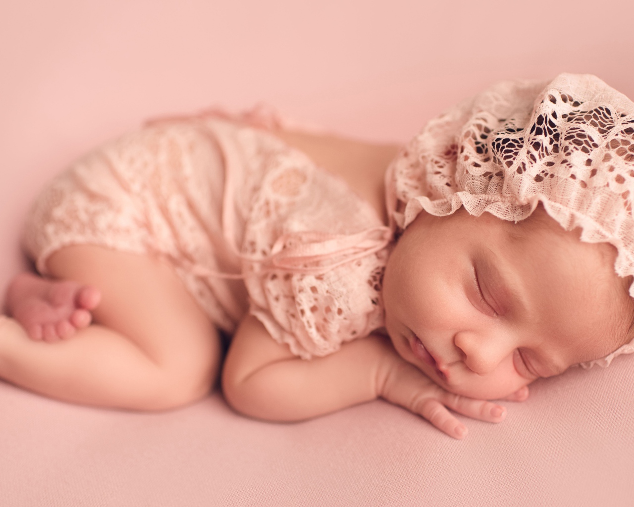 Спящий грудной ребенок в розовом костюме 