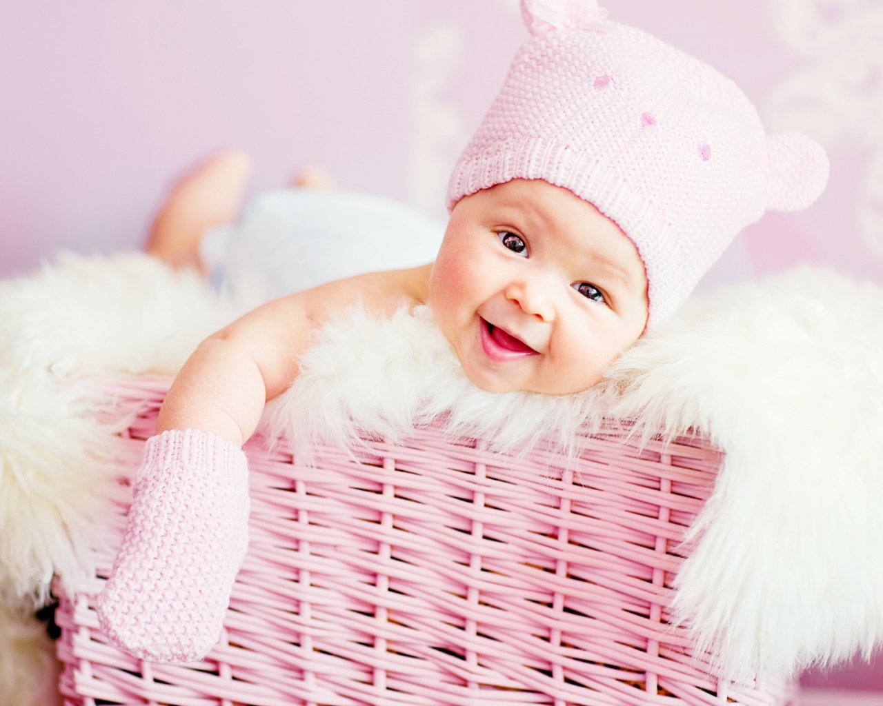 Улыбающийся грудной ребенок в шапке в розовой корзине 
