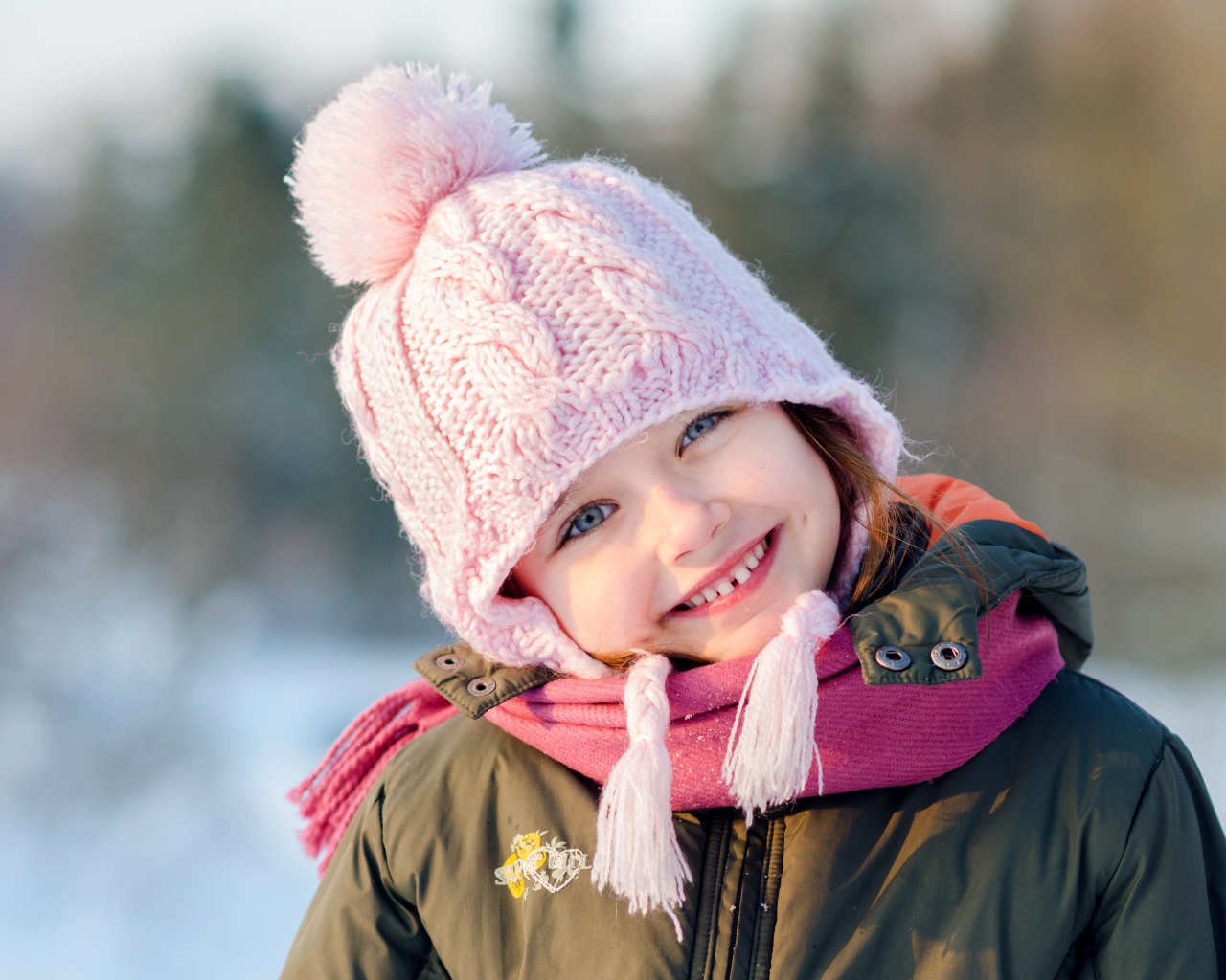 Улыбающаяся голубоглазая девочка в розовой шапке 