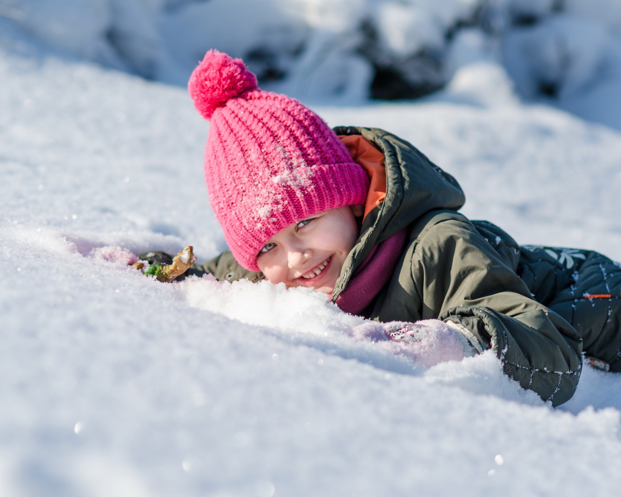 Улыбающаяся девочка лежит на снегу