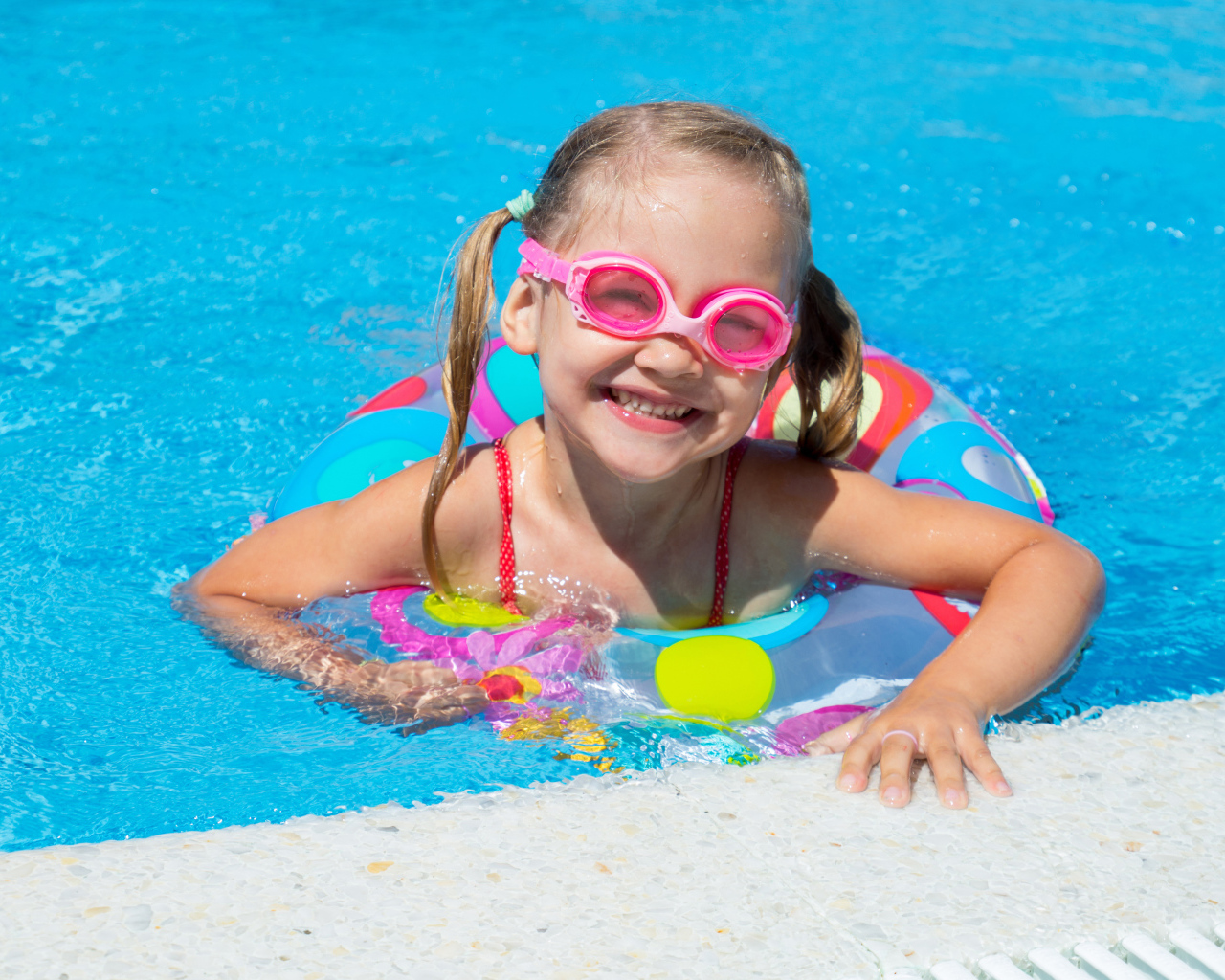 Улыбающаяся девочка с кругом в бассейне 