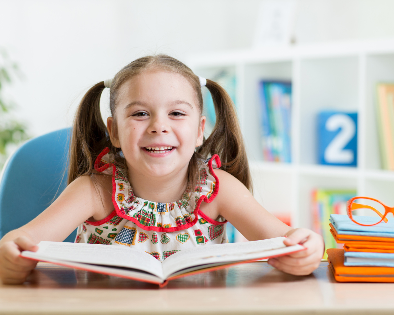 Улыбающаяся маленькая девочка с книгой 