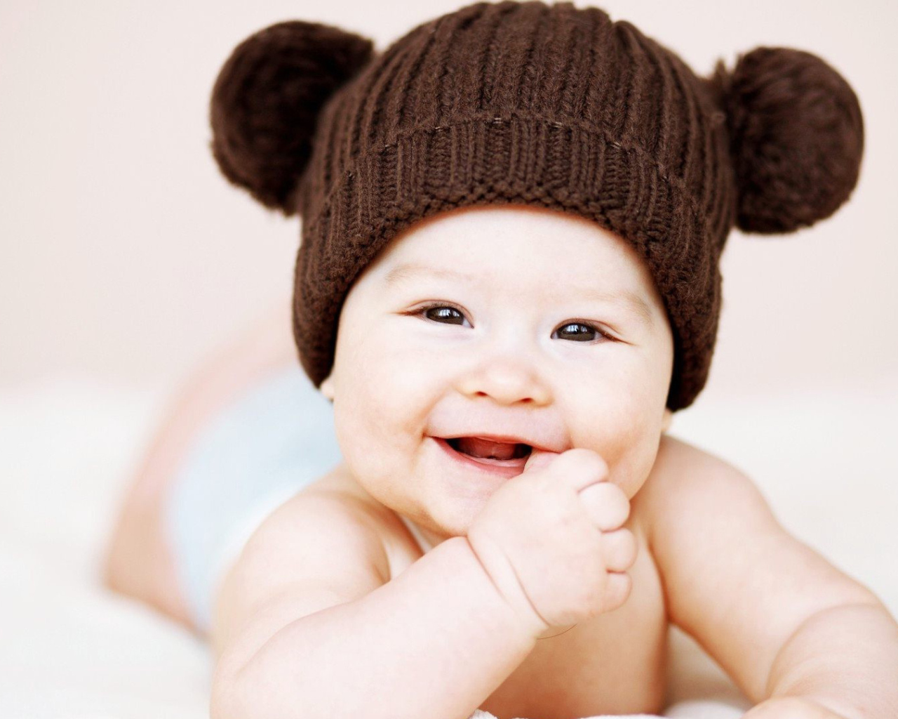 Улыбающийся грудной ребенок в коричневой шапке