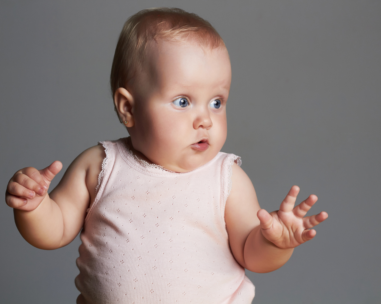 Удивленный маленький ребенок на сером фоне