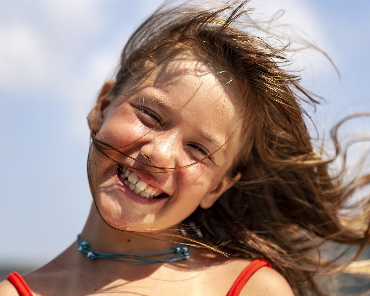 Ветер развивает волосы улыбающейся девочки