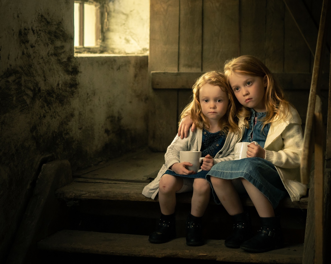 Две маленькие сестры пьют какао на ступеньках дома