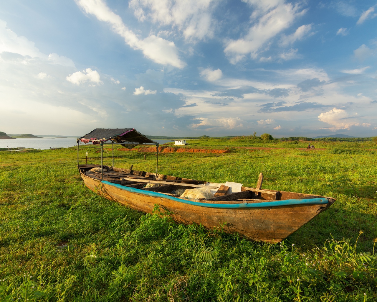Большая деревянная лодка на зеленой траве