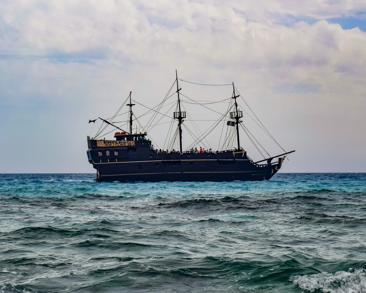 Большой черный пиратский корабль с опущенными парусами в море 