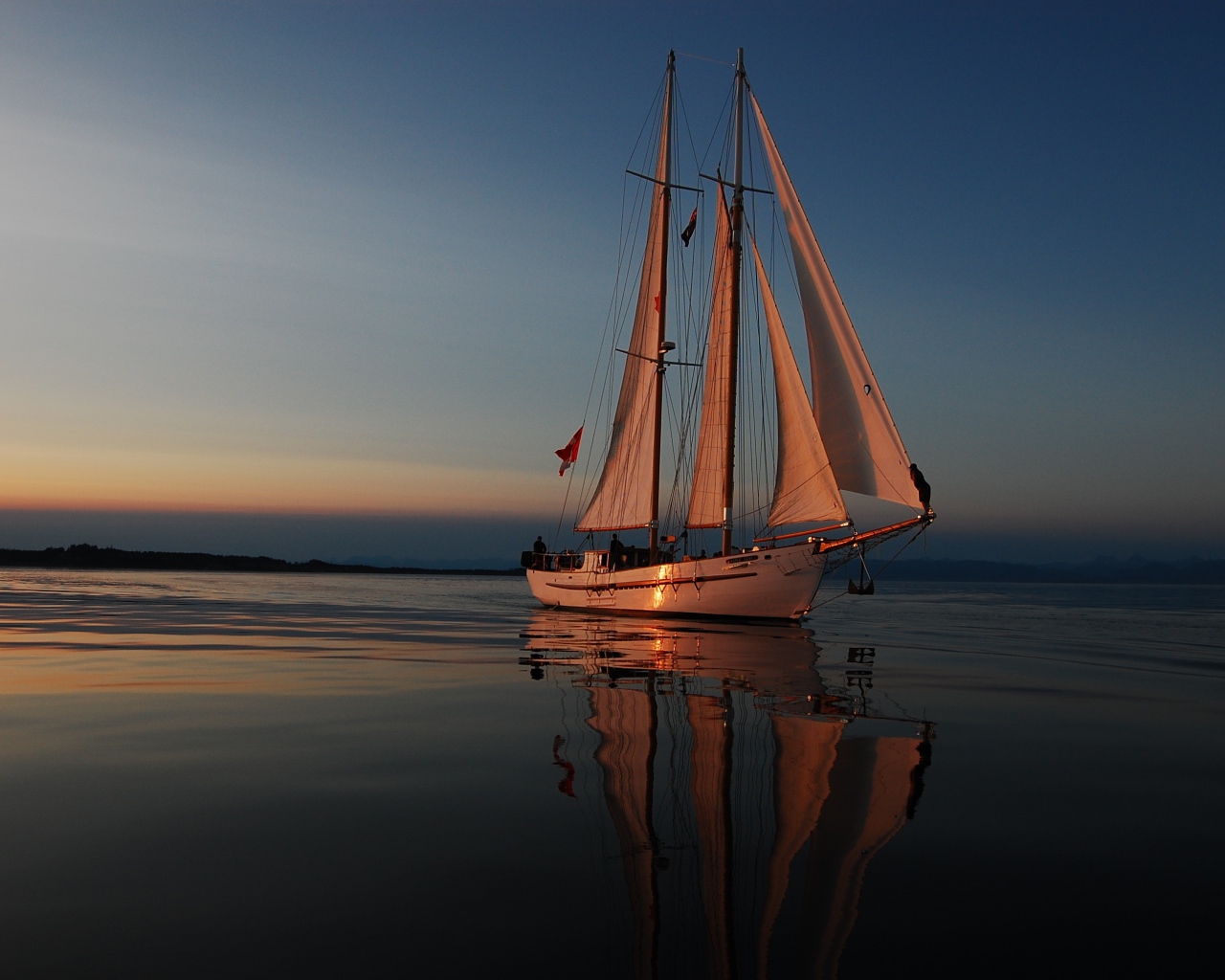 Большая яхта с белыми парусами на закате в море