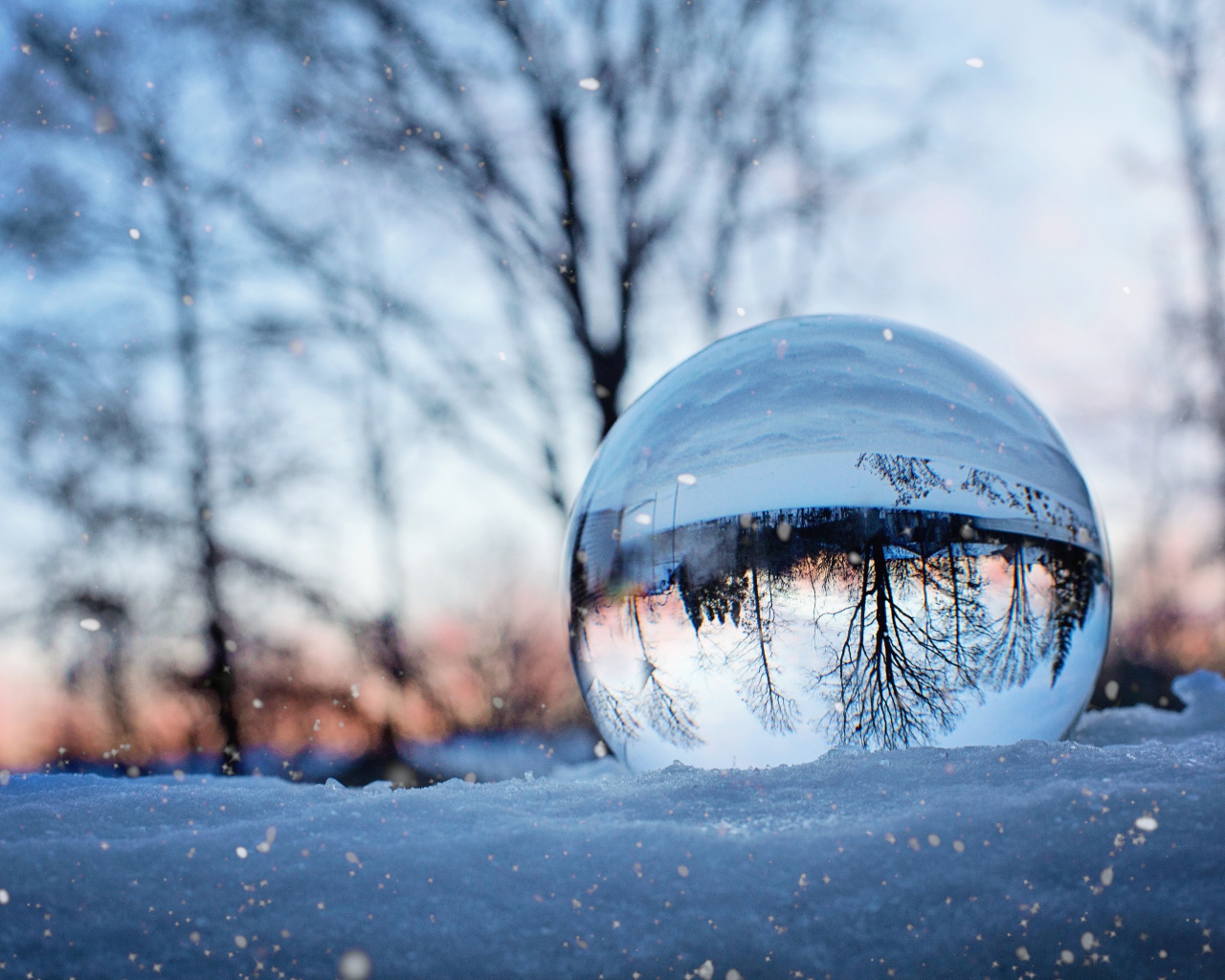 Большой стеклянный шар лежит на холодном снегу