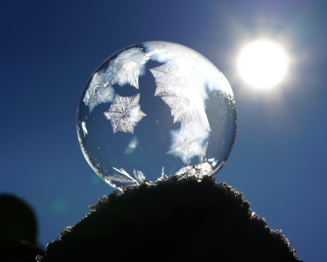 Мыльный пузырь в лучах солнца на снегу