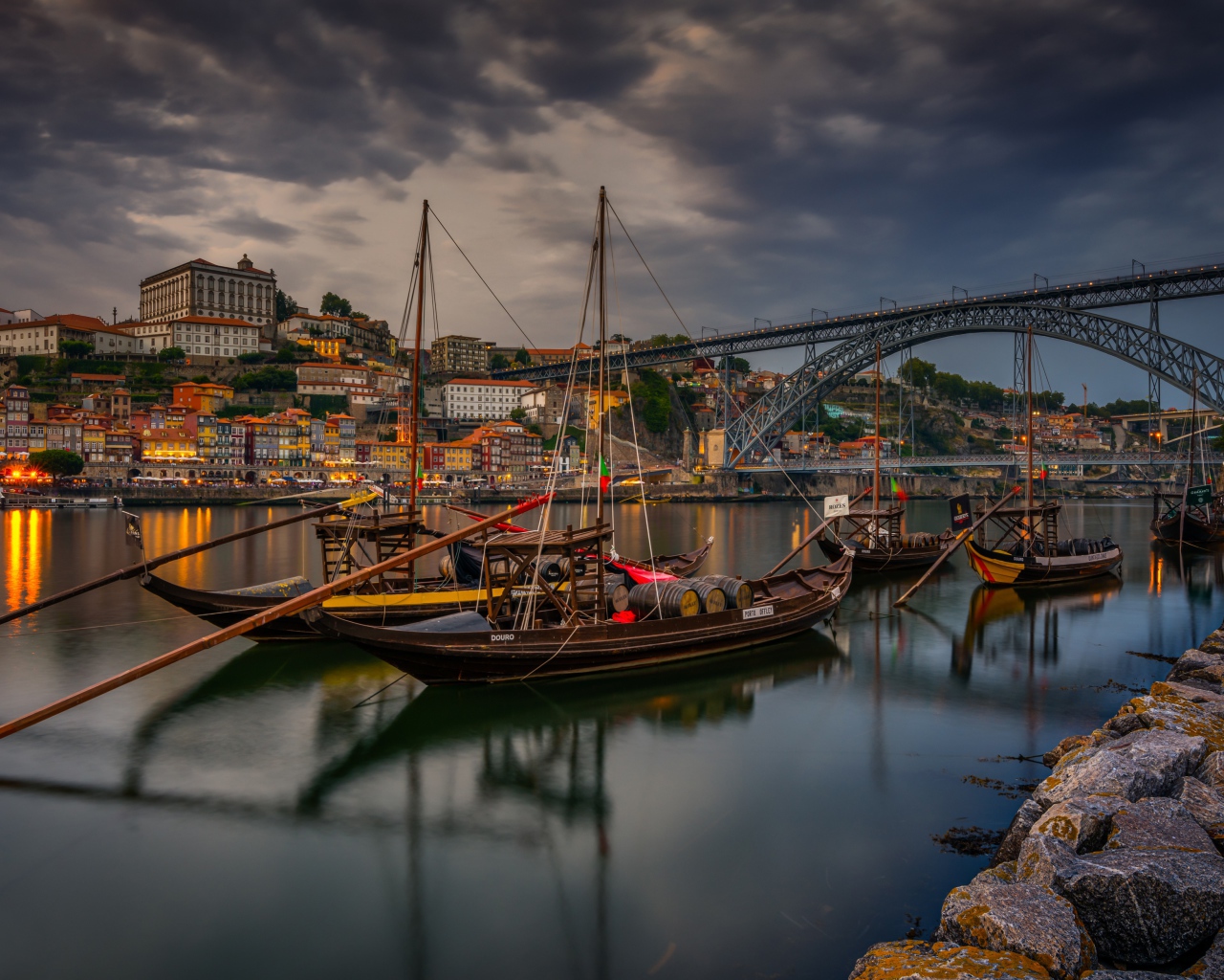 Лодки в порту на фоне моста и города на закате 