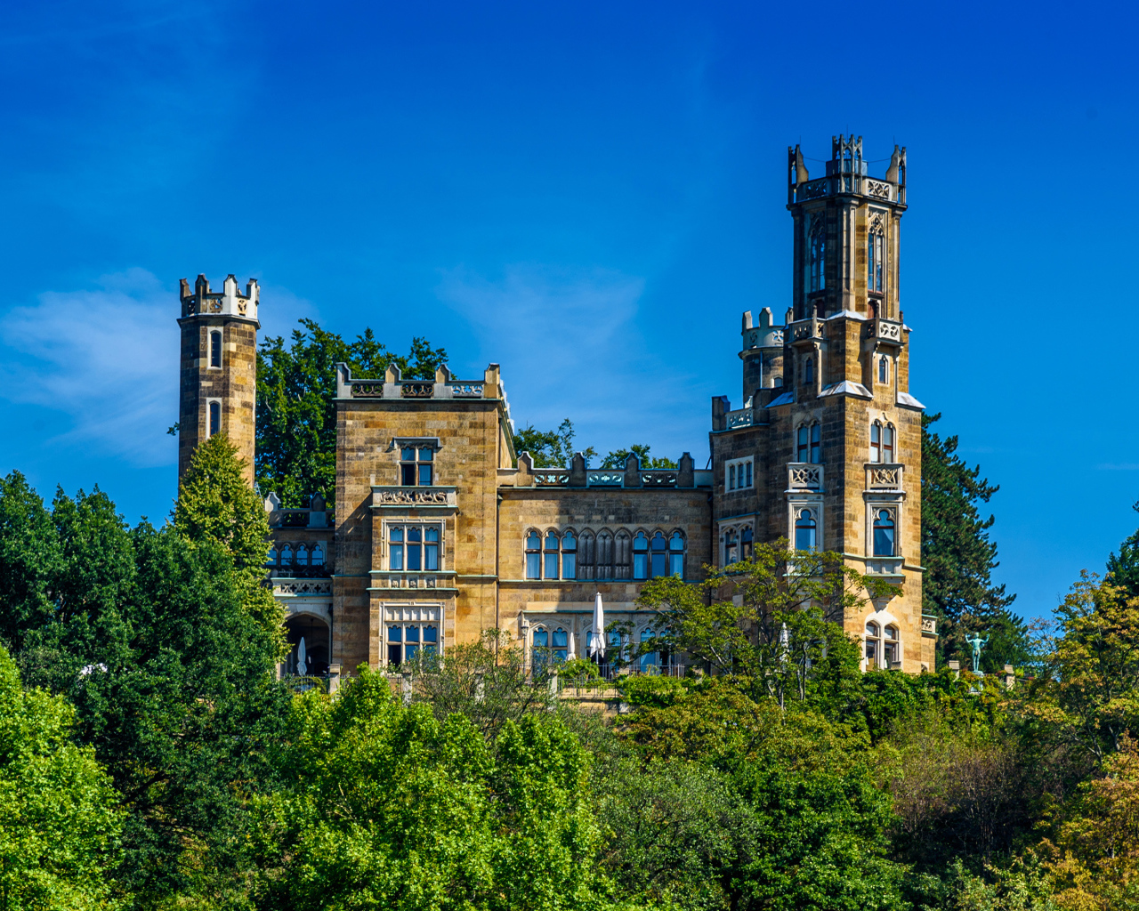Старинный замок в зарослях деревьев на фоне голубого неба, Германия
