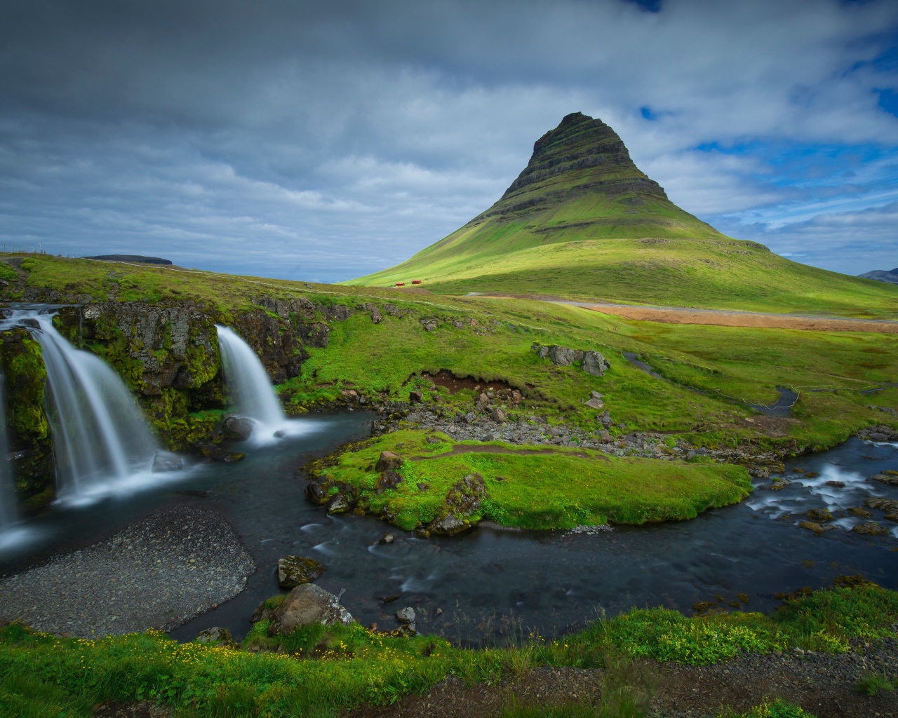 Вид на маленький водопад и покрытую зеленью гору, Исландия