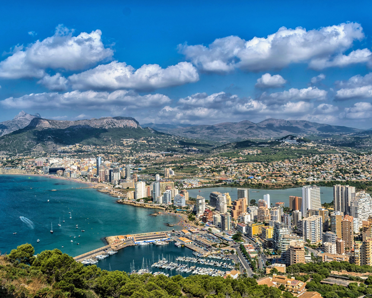 Вид на на город у гор под голубым небом с белыми облаками, Испания 