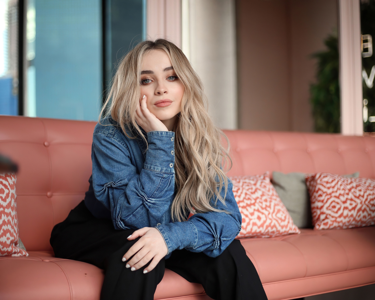 Актриса Сабрина Карпентер сидит на диване в комнате